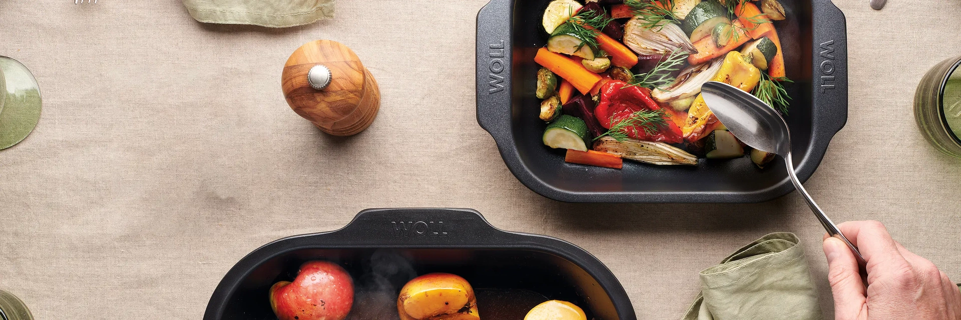 Auf dem Tisch stehen zwei heiße, viereckige Bratreine der Serie Roast it!, in denen sich dampfende Gerichte befinden.