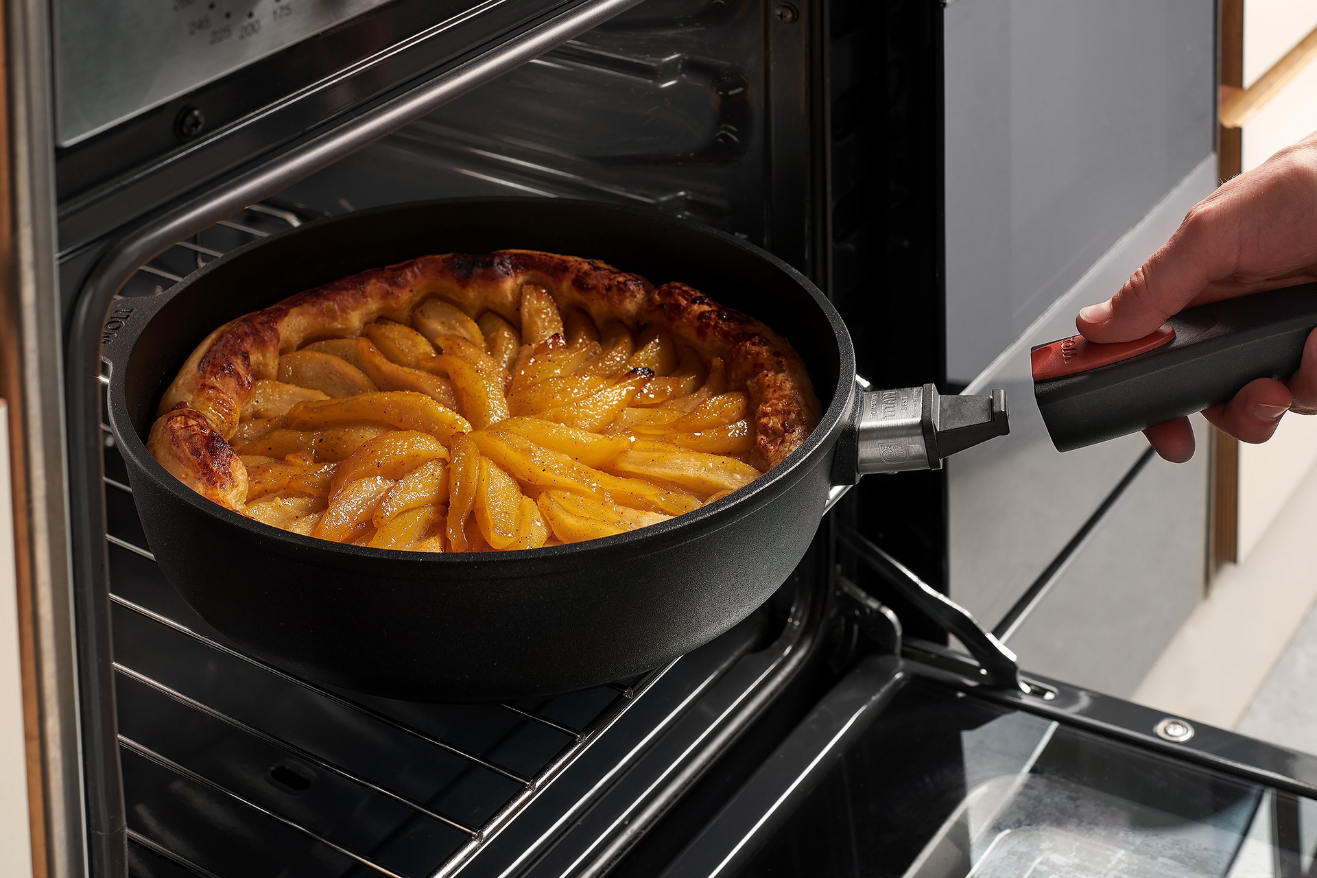 Auf dem Backofenrost steht eine runde, heiße Pfanne der Serie Titan Best mit abgenommenem Stiel, in der sich eine frisch gebackene Birnentarte aus Blätterteig befindet. Um die Tarte aus der Pfanne zu holen, wird der Stiel wieder eingerastet.