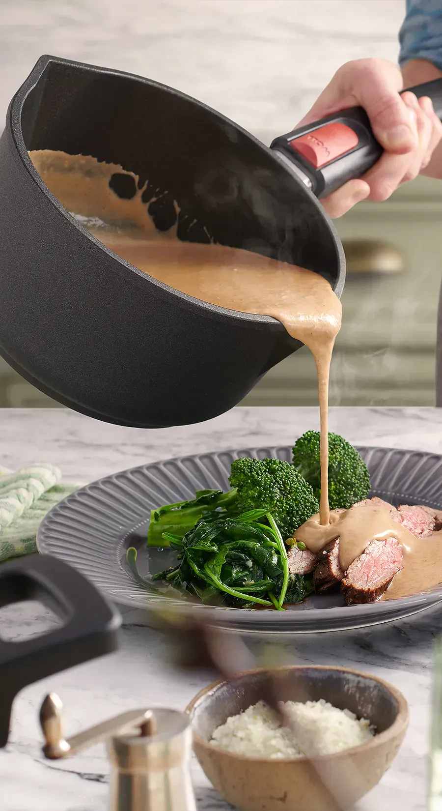 Die Soße wird direkt aus dem Stieltopf der Serie Nowo auf einen Teller gegossen, auf dem das Fleisch angerichtet ist.