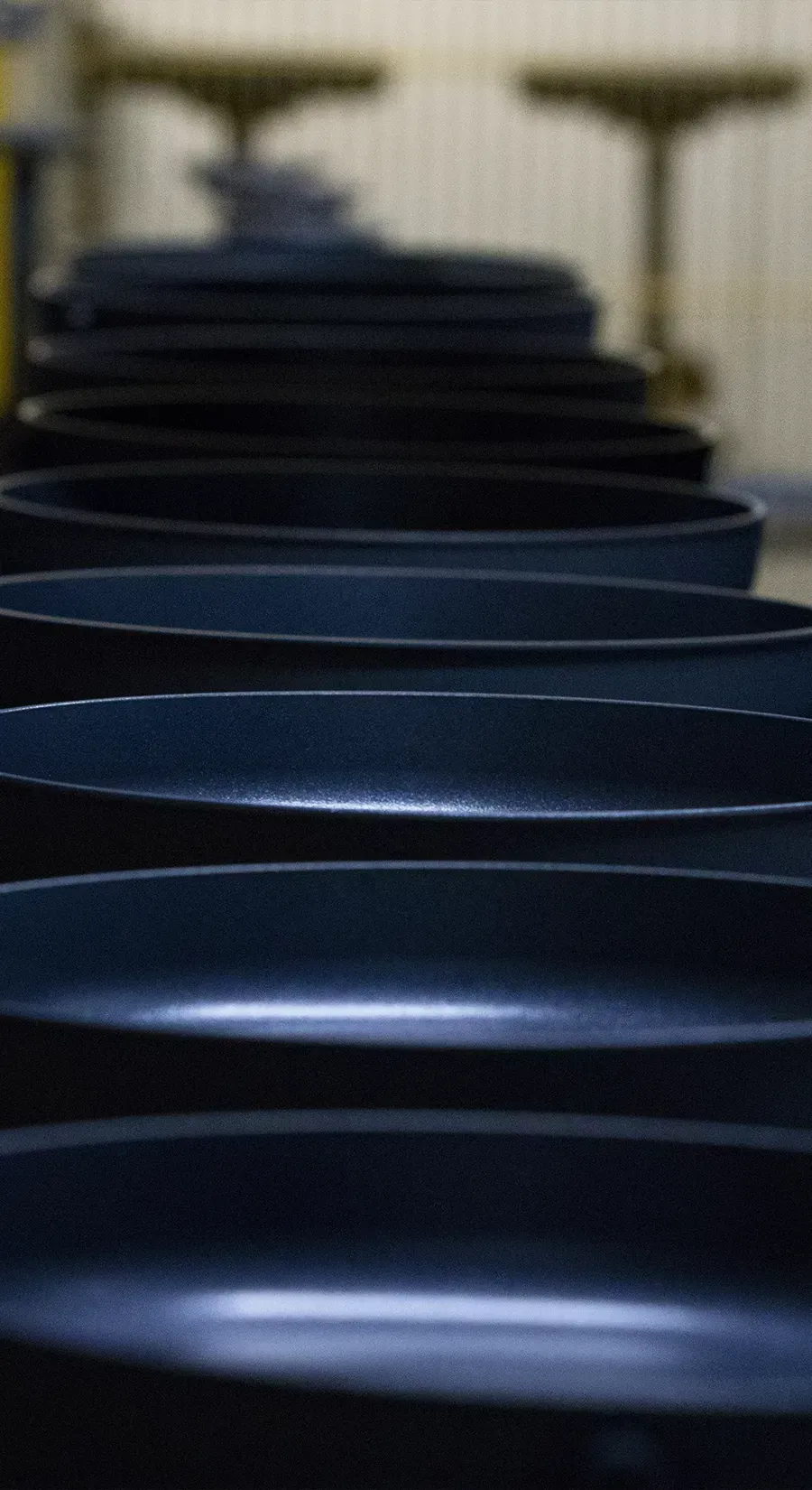 Auf dem Laufband werden mehrere beschichtete Pfannenkörper transportiert.