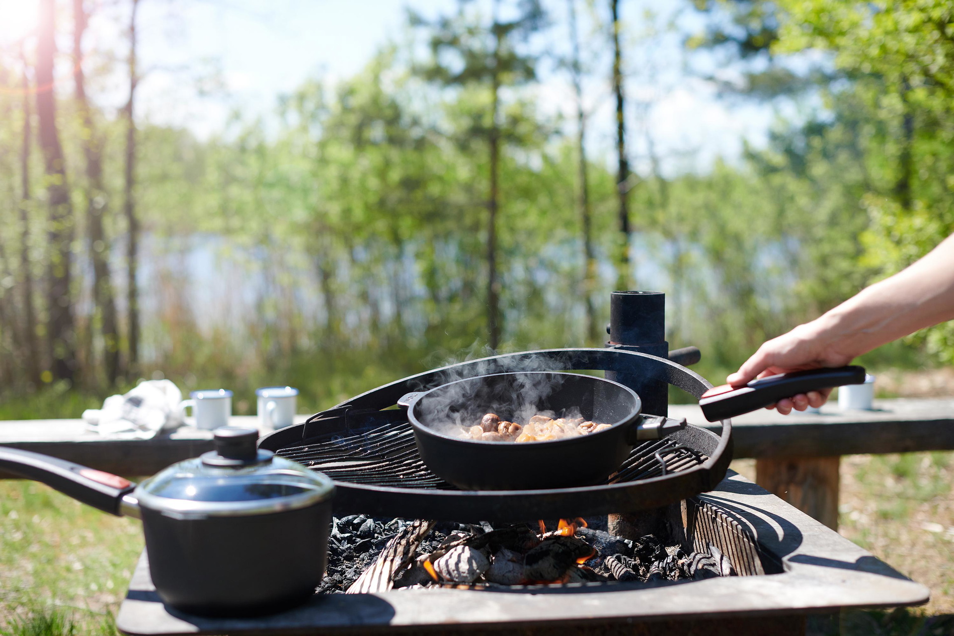 Auf dem Grill steht eine runde Titan Best Pfanne, in der ein Gericht zubereitet wird.