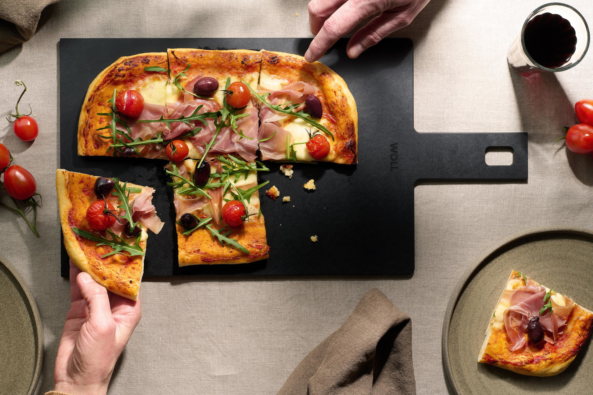 Auf dem Cut & Serve Schneidebrett mit Griff liegen frisch gebackene Pizzastücke.