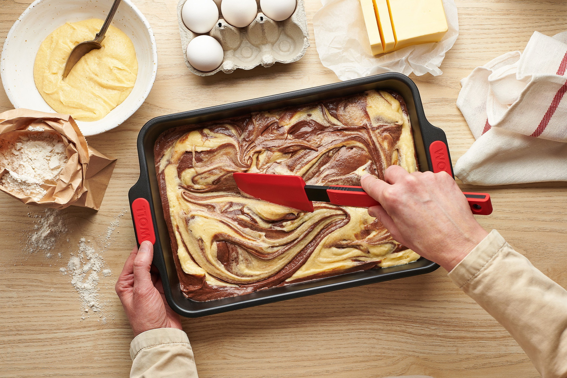 WB02_MarbleCakeMix_Mood In einer rechteckigen Let's bake! Backform wird mit einem Cock it Teigschaber roher Kuchenteig verteilt.