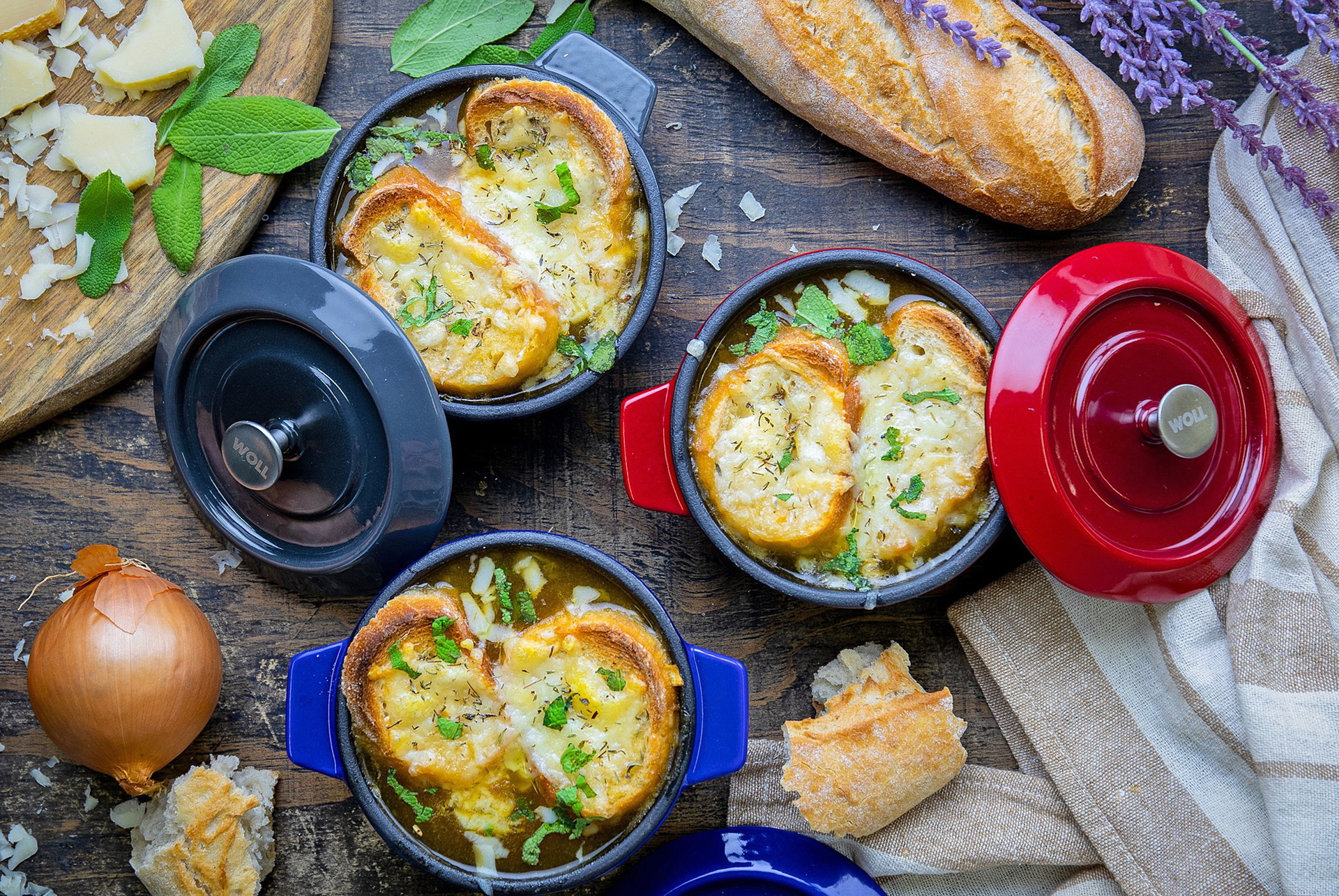In drei Mini-Kasserollen aus der Serie Iron befindet sich frisch zubereitete französische Zwiebelsuppe. Drumherum liegen weitere Zutaten sowie ein Baguette.