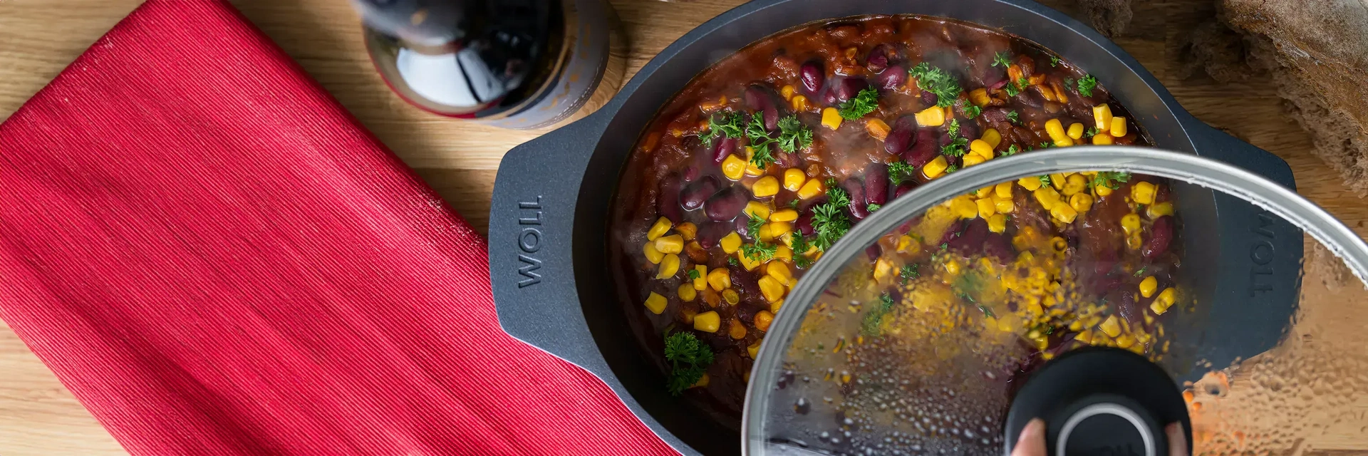 Ein Gussbräter der Serie Diamond Lite enthält Chili Sin Carne, daneben steht eine Flasche und ein rotes Tuch liegt daneben.