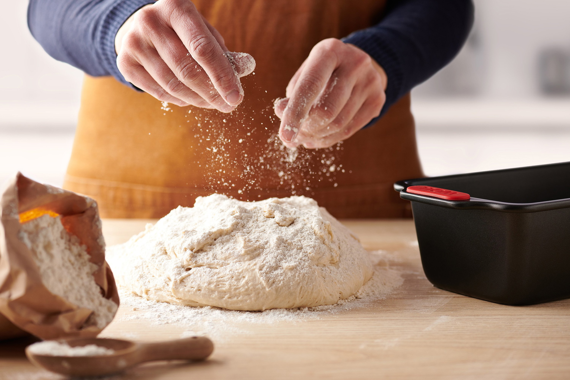 WB04_Dough_Mood Auf der Arbeitsplatte wird Teig geknetet. Eine rechteckige Let's bake! Kastenform steht daneben.