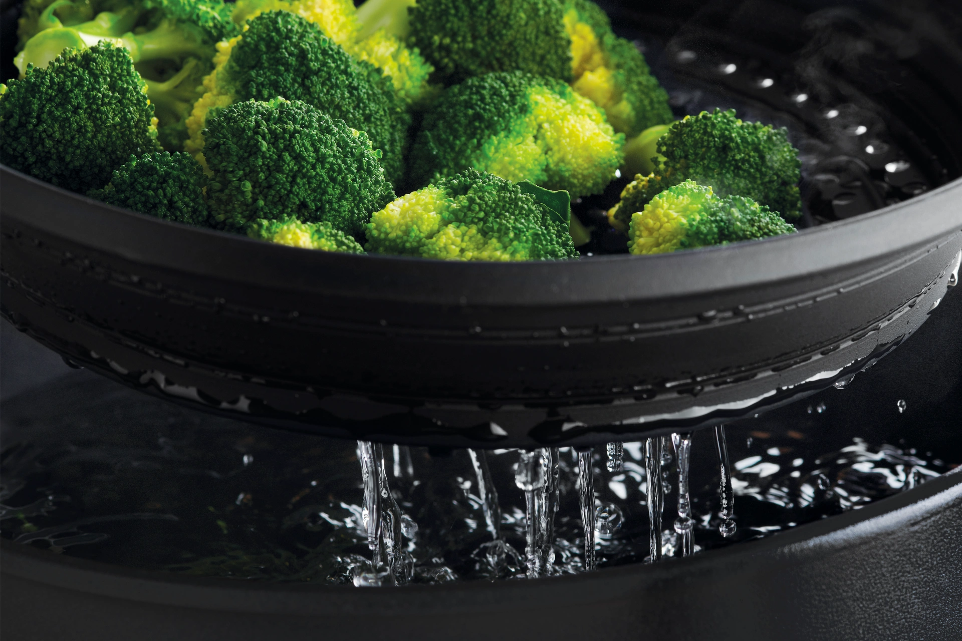 Der Steam it multifunktionale Silikoneinsatz wird aus dem Topf genommen, in dem Brokkoli gedämpft wurde. 