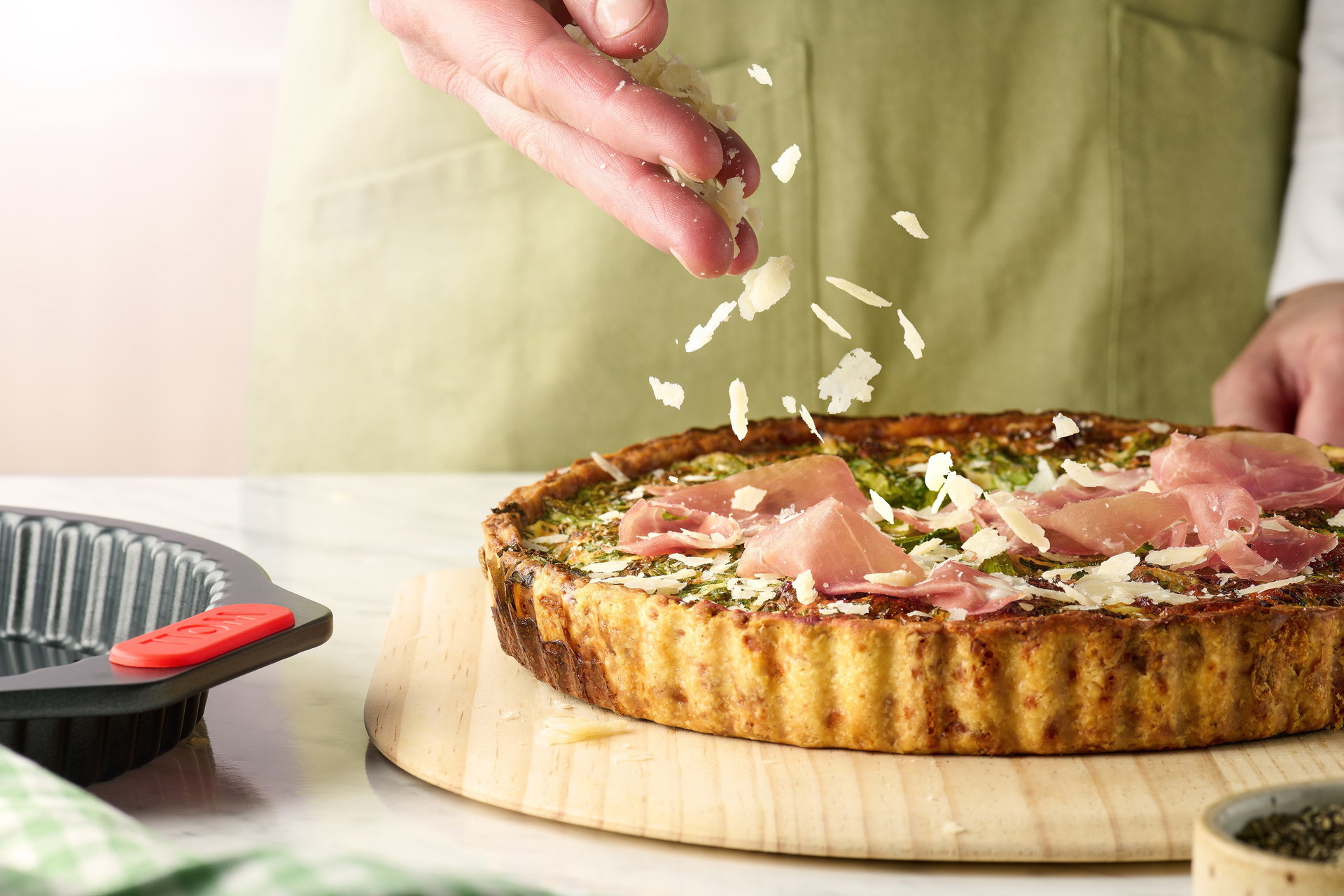 Die gebackene Kartoffel Schinken Tarte liegt auf einem Brett. Die runde Let's bake! Quiche- und Tarteform steht daneben.
