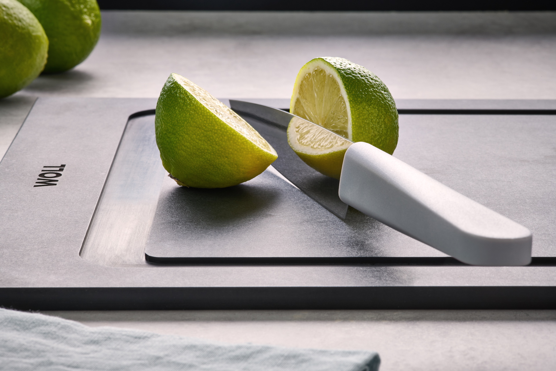 Eine Limette wurde mit einem Cuting Edge Messer auf einem Cut & Serve Schneidebrett halbiert. 