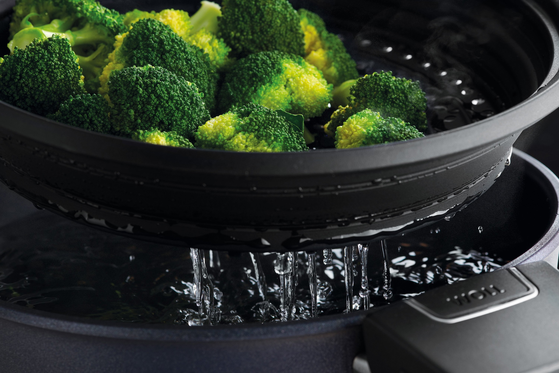 In der Nahaufnahme wird der runde Steam it multifunktionale Silikoneinsatz aus dem Topf genommen, in dem der frische Brokkoli gedämpft wurde.