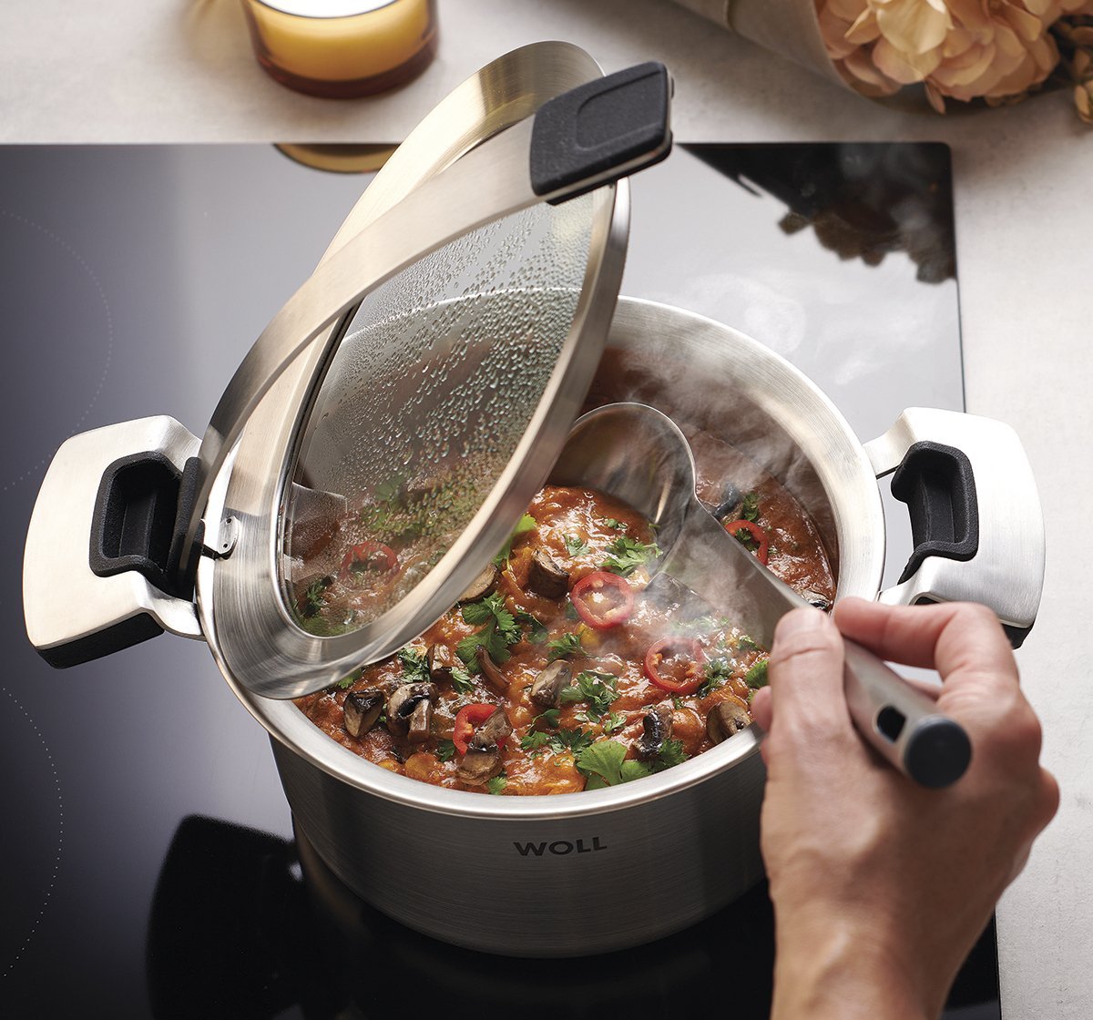 120CO_Autumn_full_RGB_1200x1120 In einem runden Concept Pro Kochtopf wird ein dampfendes Gericht zubereitet. Der Glasdeckel wurde in den Griffeinraster gestellt, sodass er offen bleibt.
