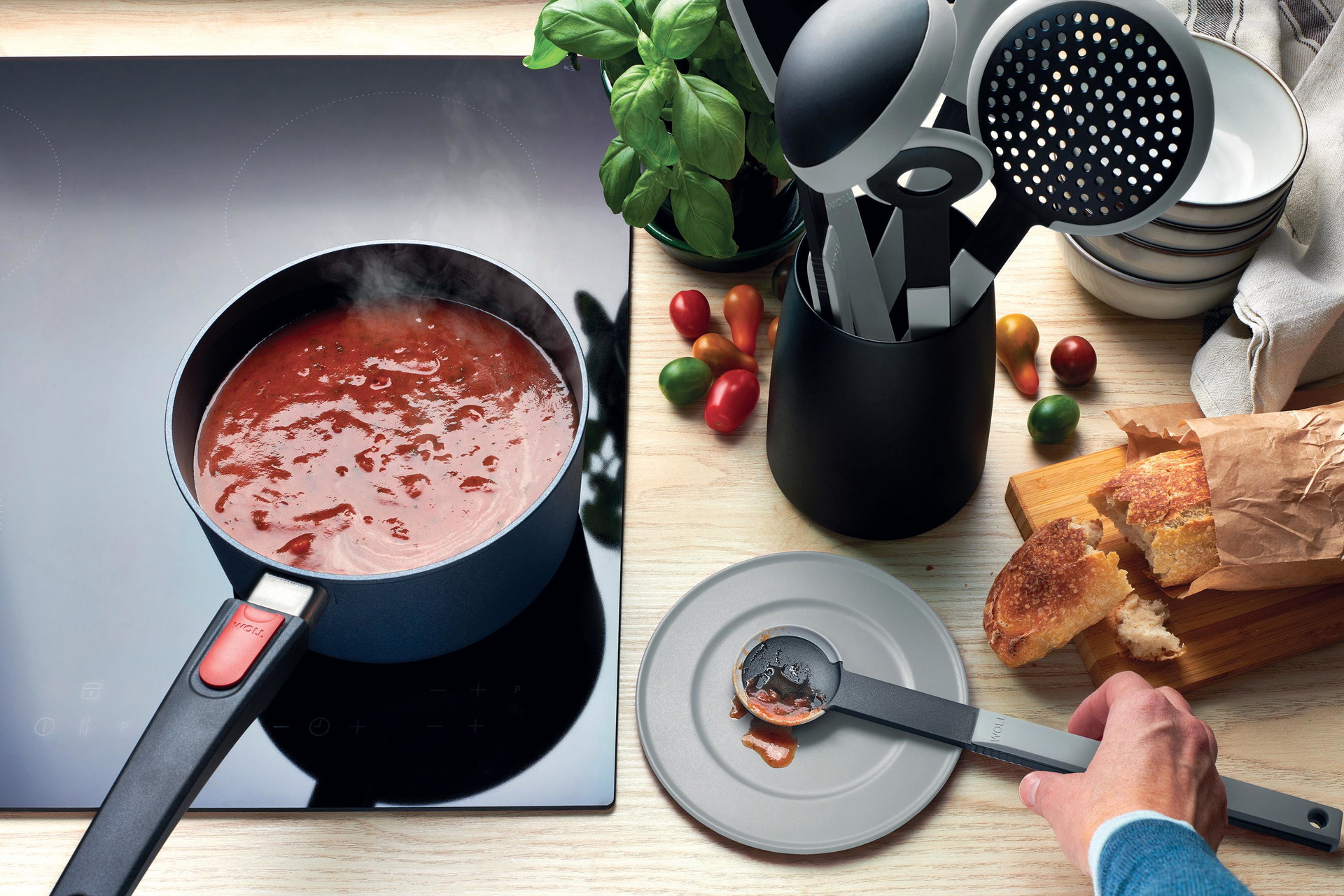 In einem runden Diamond Lite Stieltopf wird Tomatensoße gekocht. Auf der Arbeitsplatte liegen mehrere graue Cock it Küchenhelfer.