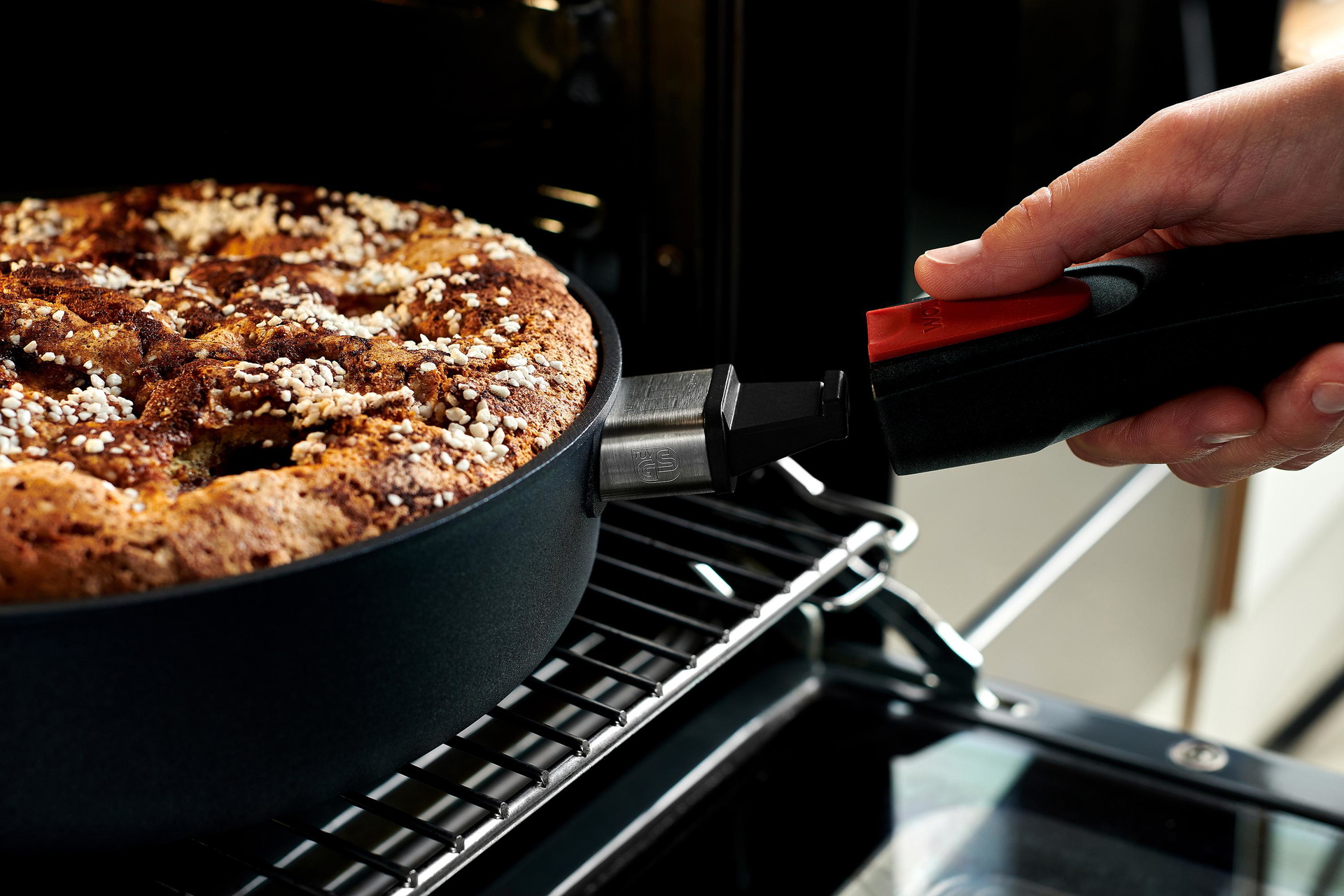 1724DPI_1724DPS_Mood_V1 Auf dem Backofenrost steht eine runde Diamond-Lite-Pfanne mit einem gebackenen Kuchen. Um die Pfanne zu entnehmen, wird der Stiel eingerastet.