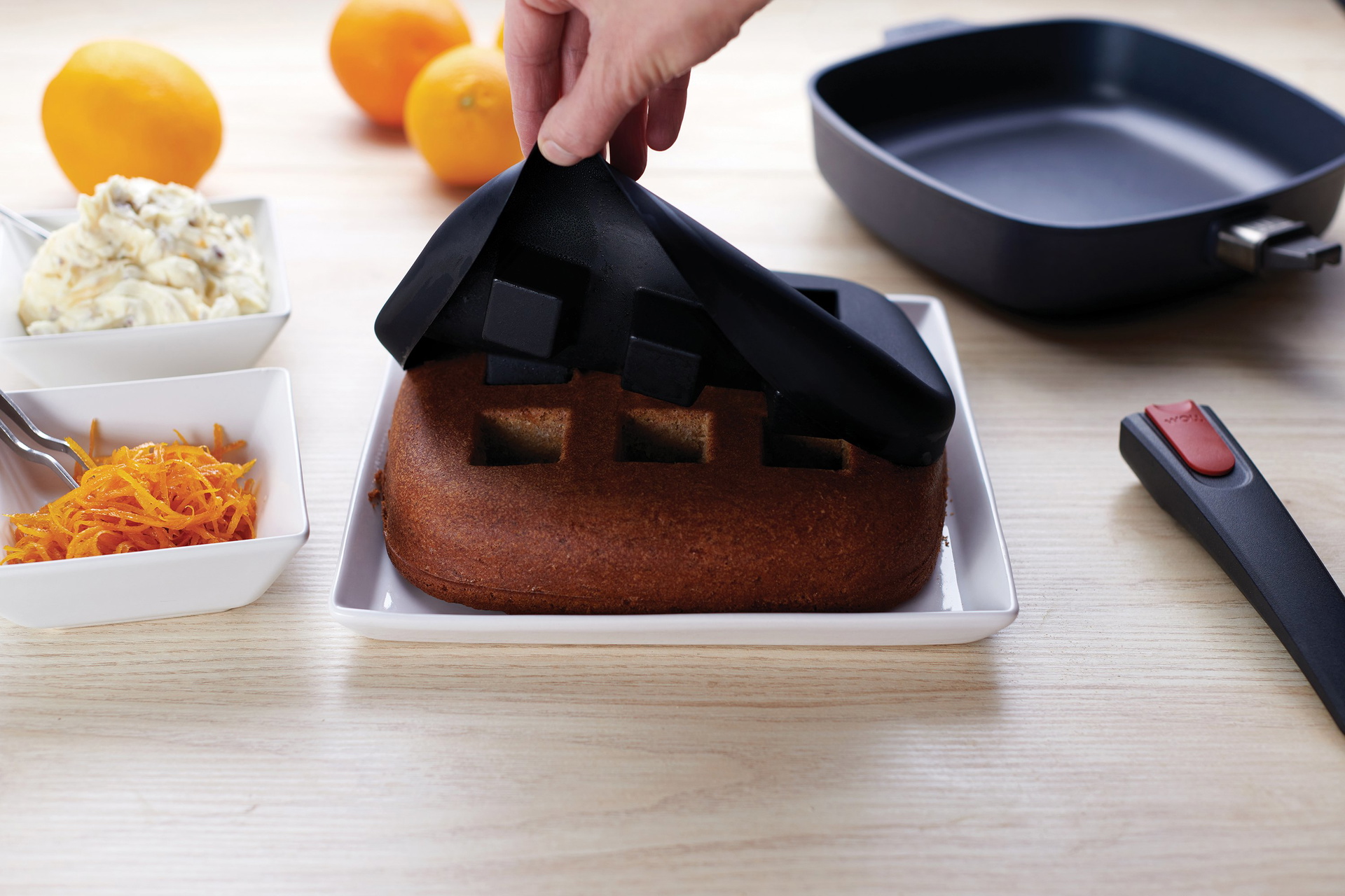 Bake-it_reveal_3000x2000_RGB Auf einem Teller steht ein frisch gebackener Kuchen, der aus dem viereckigen Bake it Silikon-Backeinsatz genommen wurde.