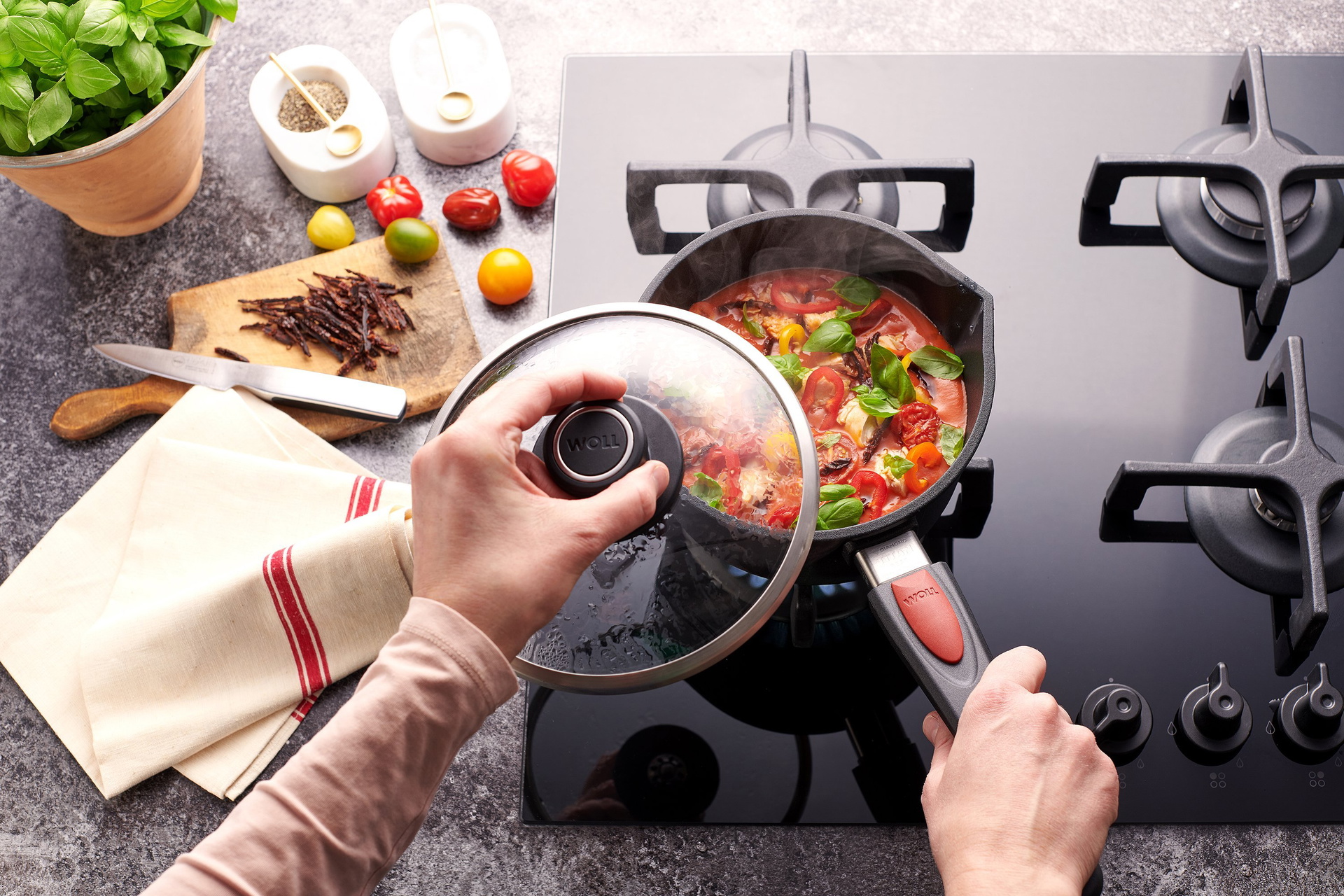 In einem Titan Best Stieltopf mit abnehmbarem Stiel wird eine Quattro Tomatensuppe mit Paprika und gegrilltem Hähnchen zu bereitet.Der Deckel wurde abgenommen. Außerhalb des Kochfelds liegen weitere Zutaten.