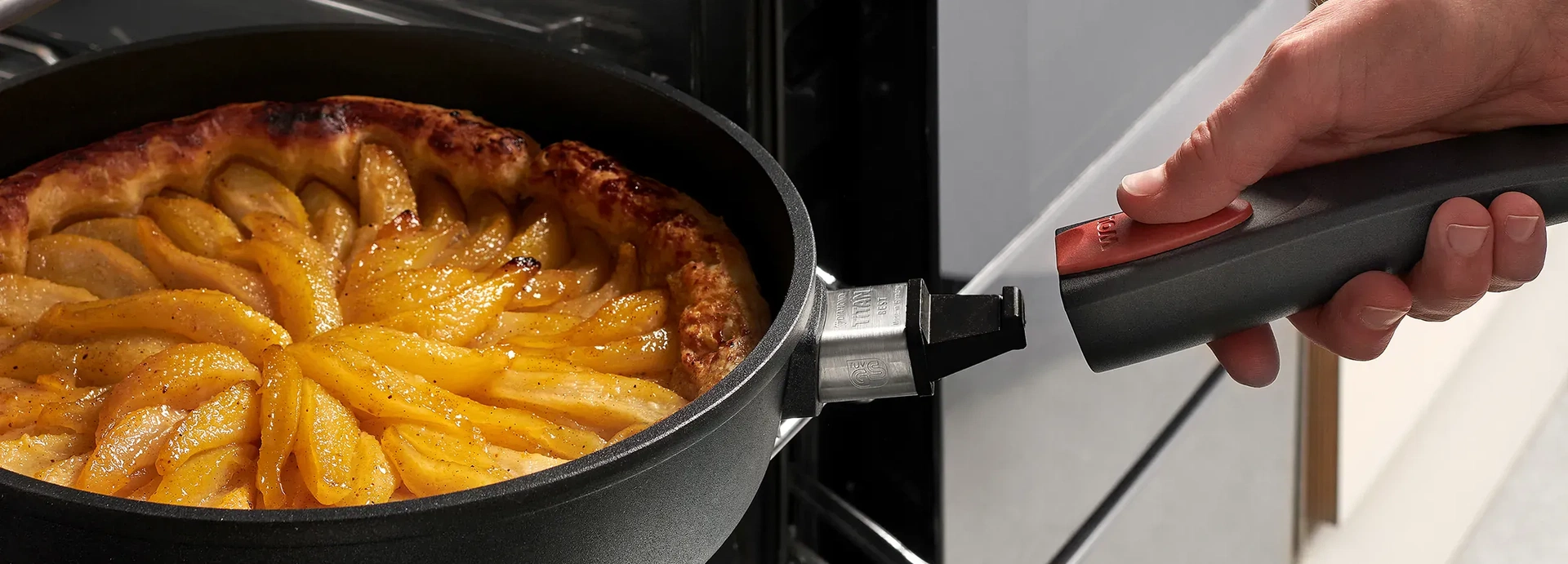 Auf dem Backofenrost steht eine runde, heiße Pfanne der Serie Titan Best, die ein Gericht beinhaltet. Um die Pfanne aus dem Ofen zu holen, wird der Pfannenstiel wieder eingerastet.