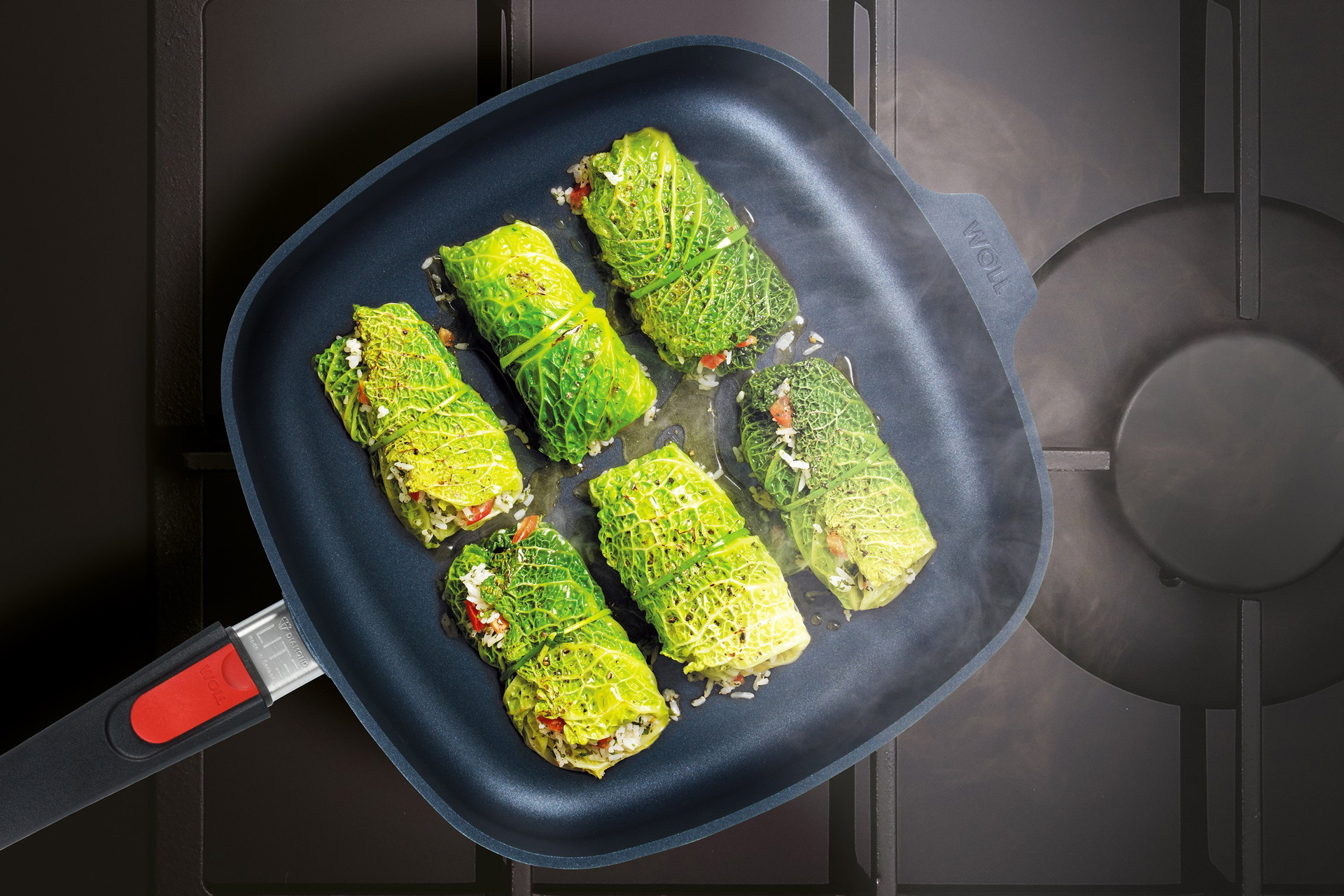 Auf dem Herd steht eine viereckige, heiße Diamond-Lite-Pfanne mit abnehmbarem Stiel. Darin befindet sich frisch zubereitete, dampfende Kohlrouladen.