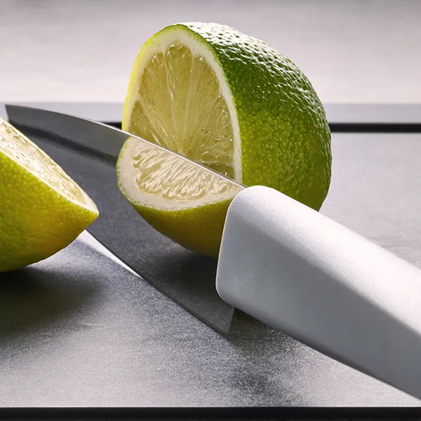 Eine Limette wurde mit einem Messer der Serie Cutting Edge auf einem Schneidebrett halbiert.