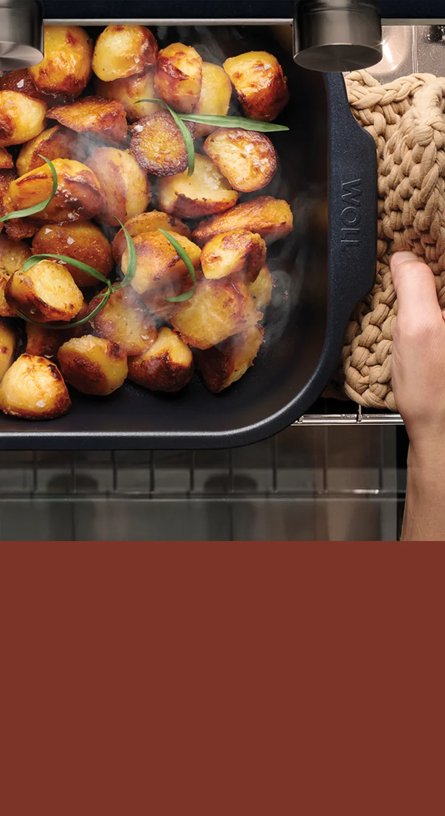 Eine Roast-it-Form mit dampfenden, gerösteten Kartoffelhälten darin wird aus dem Backofen genommen.