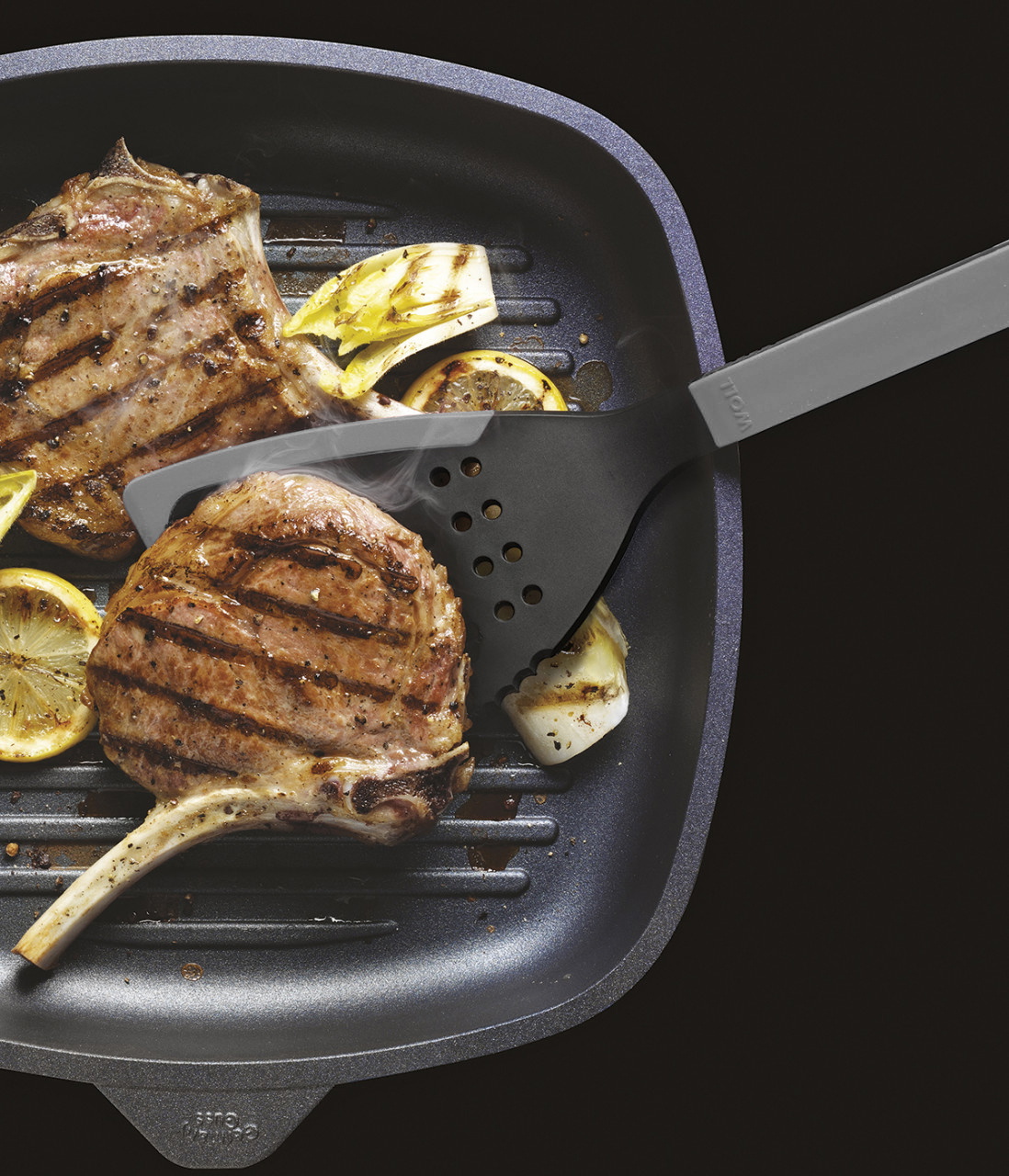 In einer viereckigen Grillpfanne werden zwei Fleischstücke angebraten und mit einem grauen Cock it Jumbo Pfannenwender gewendet.